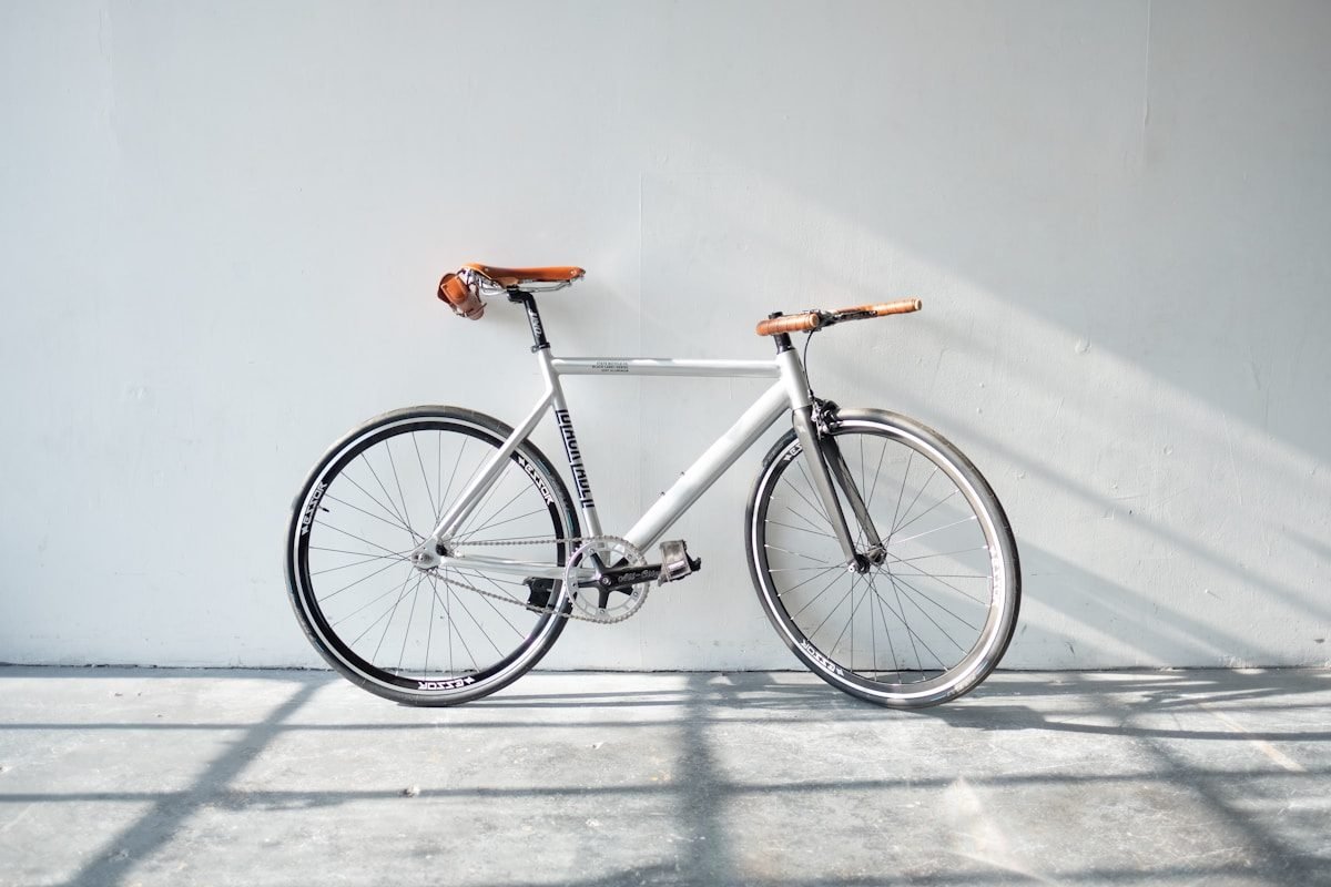 A silver single-speed city bike photographed side-on against a pale wall