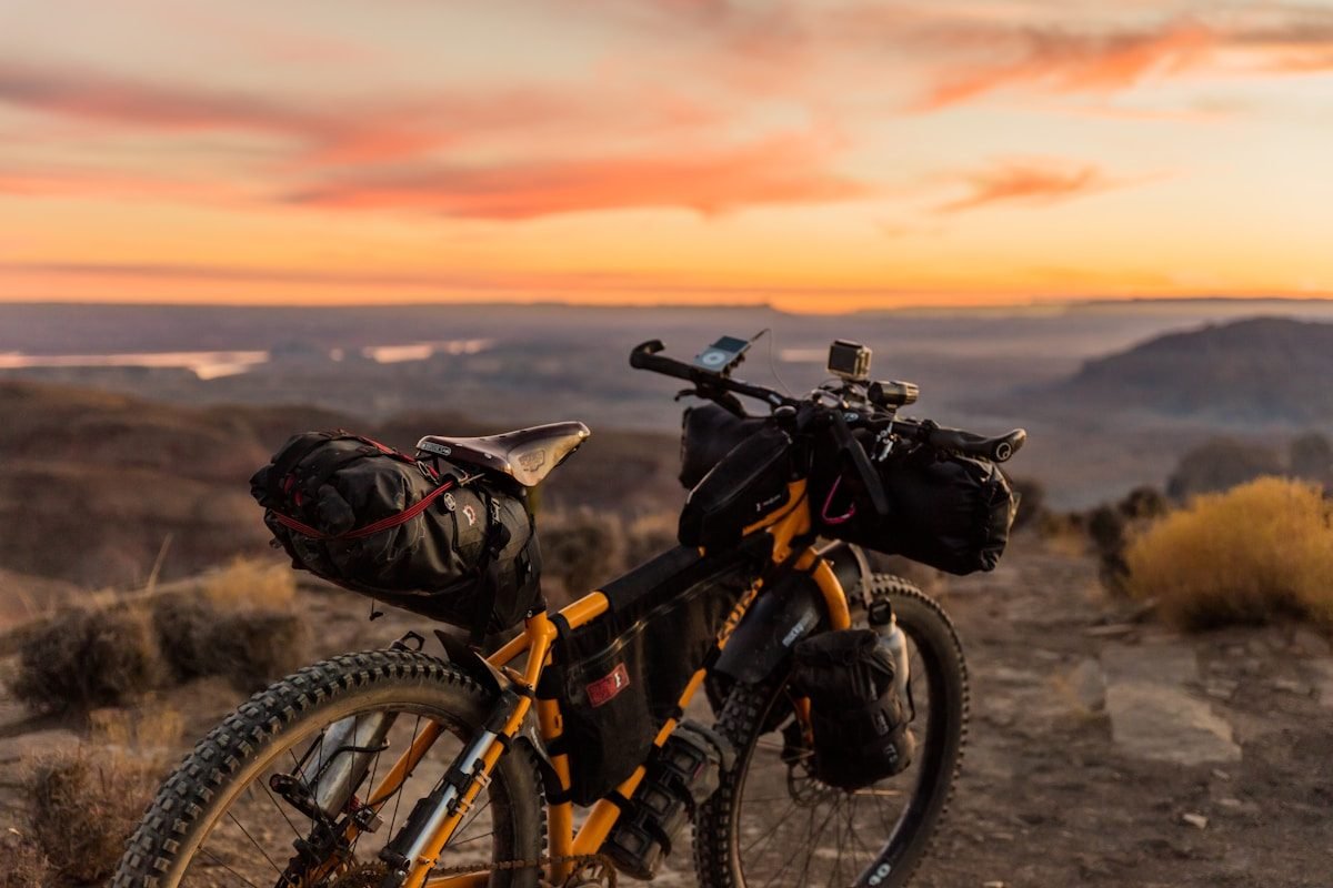 A loaded touring bicycle with luggage bags silhouetted against a sunset