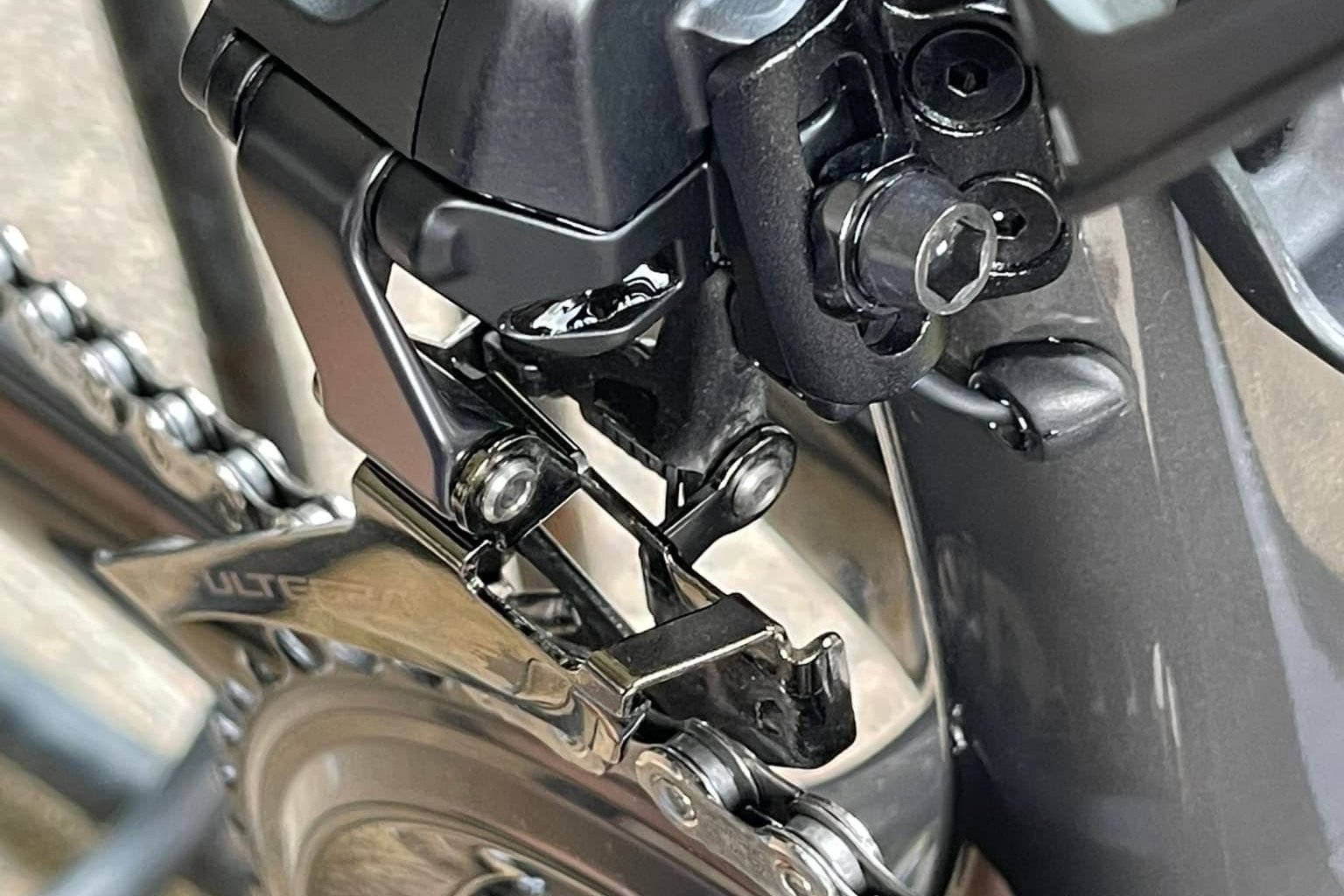 A close-up of a bicycle chain running through the front derailleur and over the chainring