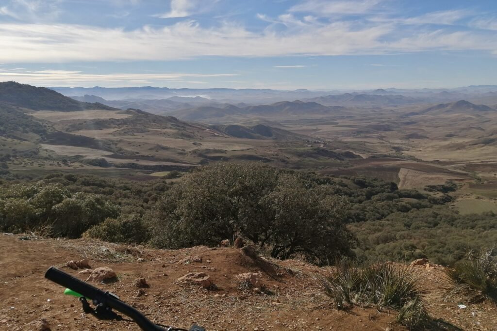 A wide view over the Middle Atlas from the road between El Hajeb and Azrou, with mountain bike handlebars in the foreground